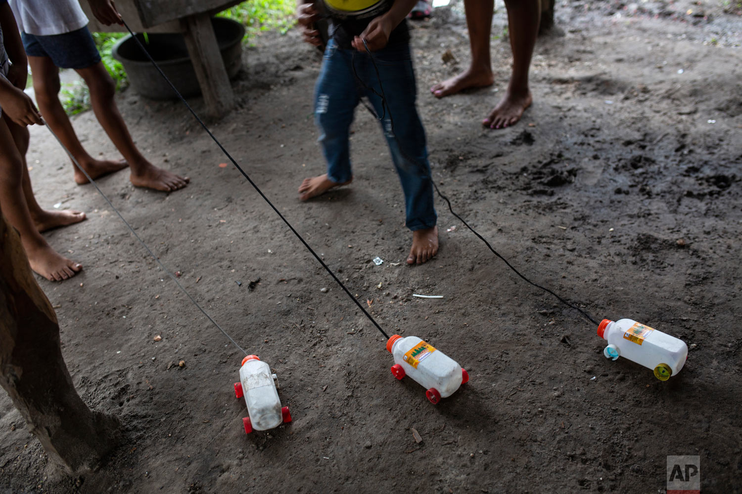  In this Feb. 6, 2018 photo, children hold onto to their toys made with recycled material, in Puerto Lempira, Honduras. A sign of the poverty, boys crafted toy trucks from plastic juice boxes with lids for wheels. For grown-ups, the only option they’