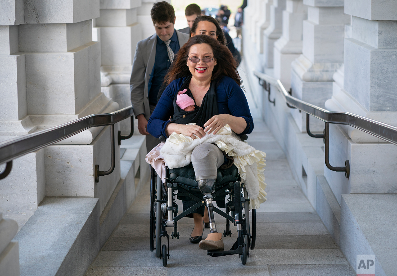 Sen. Tammy Duckworth, D-Ill., arrives at the Capitol for a close vote with her new daughter, Maile, bundled against the wind, in Washington, Thursday, April 19, 2018. In an historic change in Senate rules, the lawmakers decided to allow babies of members on the floor during votes. (AP Photo/J. Scott Applewhite)