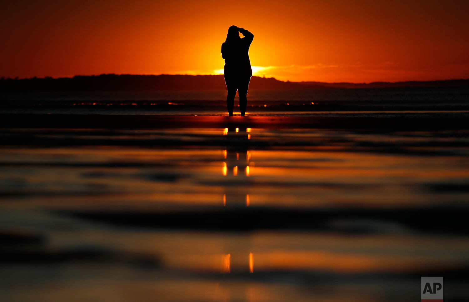 Consuello Jessop, of Providence, R.I., photographs the sunrise at Ocean Park, Thursday, July 12, 2018, in Old Orchard Beach, Maine. (AP Photo/Robert F. Bukaty)