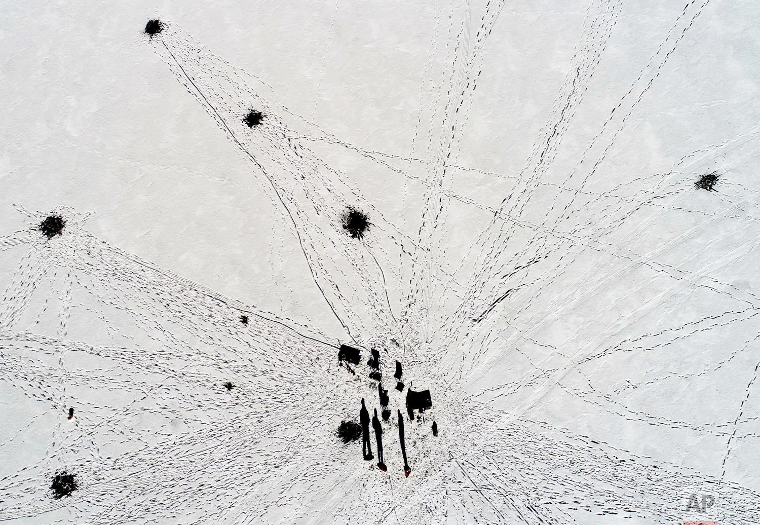 Ice fishermen on the Cheshire Reservoir cast long winter shadows Thursday, Dec. 27, 2018, Cheshire, Mass. The ice is 6 inches thick where the men are fishing, but open water exists near areas with current near the outlets; only experts should venture out on the ice. (Ben Garver/The Berkshire Eagle via AP)