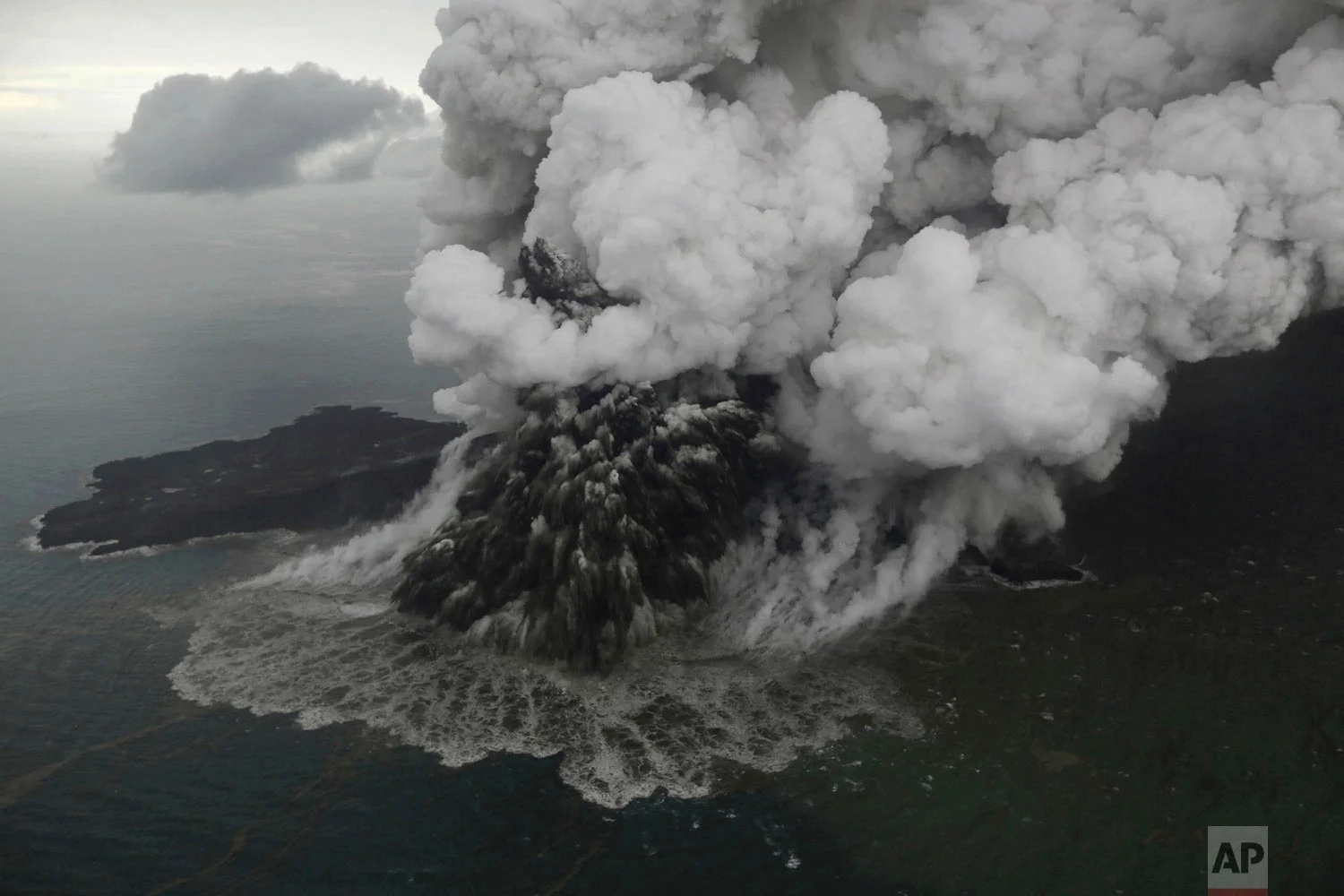 Plumes rise from Mount Anak Krakatau as it erupts in the Java Strait, Indonesia on Sunday, Dec. 23, 2018. A deadly tsunami followed an eruption and apparent undersea landslide on the volcano, gushing ashore without warning during a busy holiday weekend. (Nurul Hidayat/Bisnis Indonesia via AP)