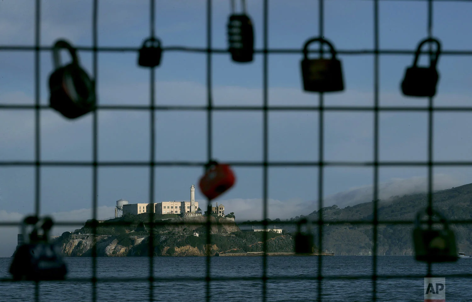 Alcatraz Island is shown behind a locks attached to a pier fence in San Francisco, Saturday, Dec. 22, 2018. A partial federal shutdown has been put in motion because of gridlock in Congress over funding for President Donald Trump's Mexican border wall. The company that provides ferry services to Alcatraz Island kept its daytime tours but canceled behind-the-scenes and night tours. (AP Photo/Jeff Chiu)