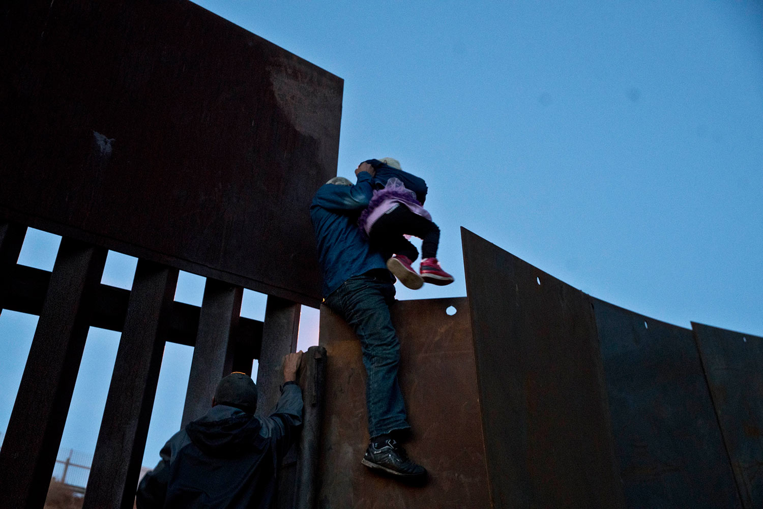  A Honduran migrant helps a young girl cross to the American side of the border wall, in Tijuana, Mexico, Sunday, Dec. 2, 2018. (AP Photo/Ramon Espinosa) 