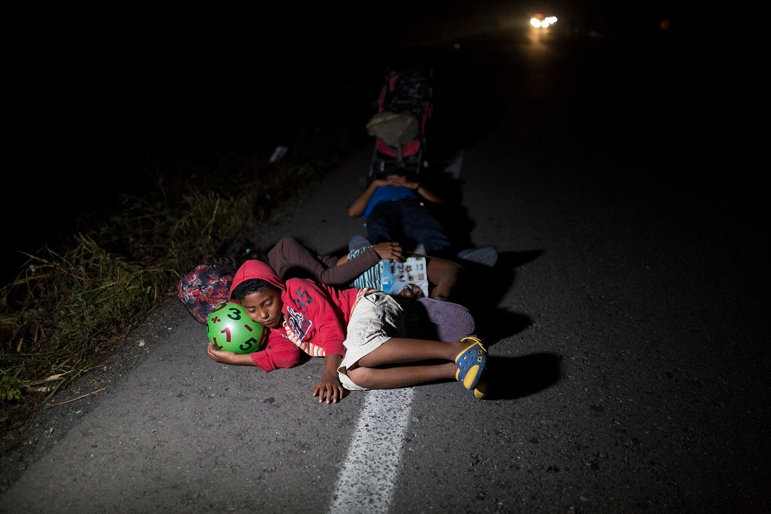  Jason, 11, sleeps using a toy ball as pillow during a break from walking early morning on the road that connects Pijijiapan with Arriaga, Mexico, on Oct. 26, 2018. (AP Photo/Rodrigo Abd) 