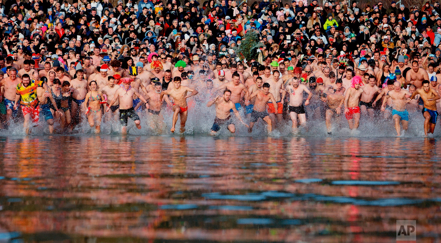 Swimmer run into the chilly water of Lake Balaton during the 8th annual New Year's swimming in Szigliget, southwest of Budapest, Hungary, Tuesday, Jan.1, 2019. (Gyorgy Varga/MTI via AP)