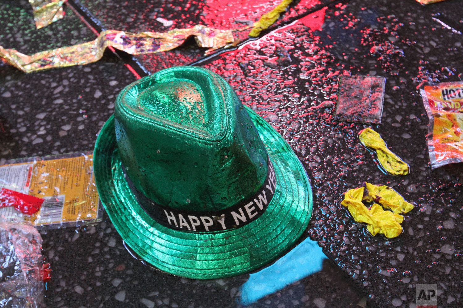 A "Happy New Year" hat lies on the wet ground along with other items following the celebration in New York's Times Square, early Tuesday, Jan. 1, 2019. (AP Photo/Tina Fineberg)