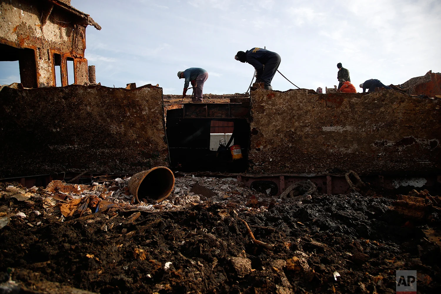 In this Monday, Nov. 5, 2018 photo, in a shipyard of Perama, west of Athens, workers cut up the rusted remains of a ferry that was recovered after spending years as a shipwreck. (AP Photo/Thanassis Stavrakis)