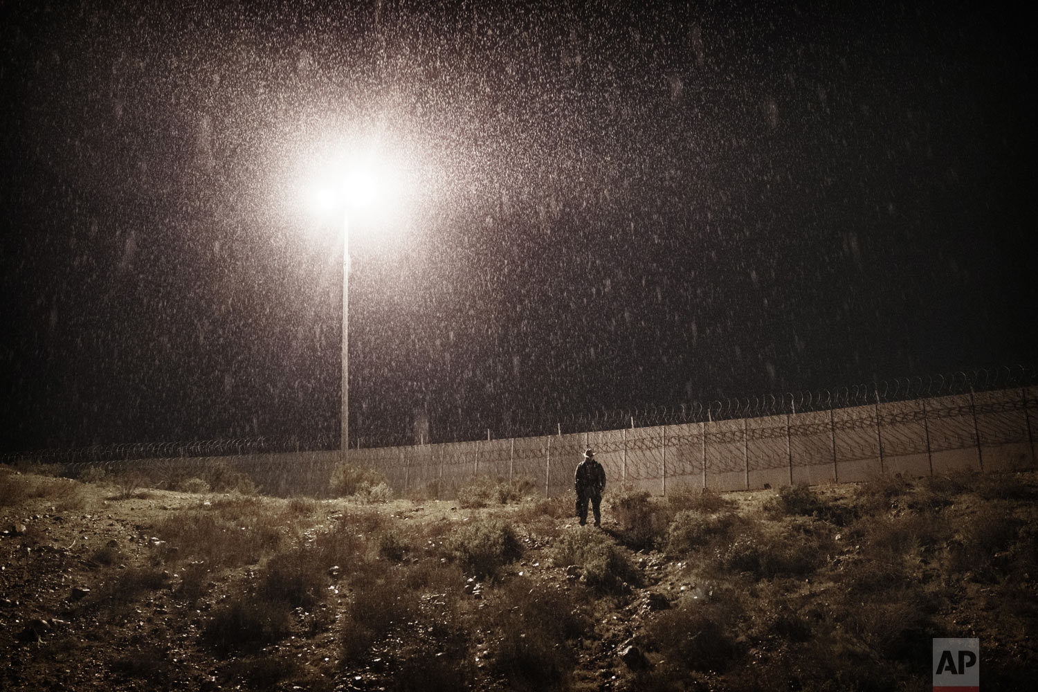 A U.S. Border Protection officer stands under the rain as he watches the border fence between San Diego, Calif., and Tijuana, Mexico, Tuesday, Jan. 1, 2019. Discouraged by the long wait to apply for asylum through official ports of entry, many migra