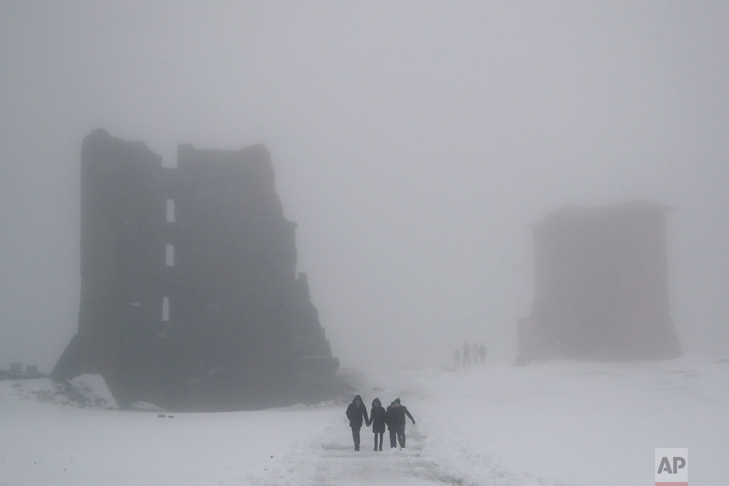  People walk past the ruins of a medieval castle on a foggy day in the Belarusian town of Novogrudok, 150 kilometers (93 miles) west of the capital Minsk, Sunday, Dec. 30, 2018, as temperature hovered around 2 degrees Celsius (35 Fahrenheit). (AP Pho