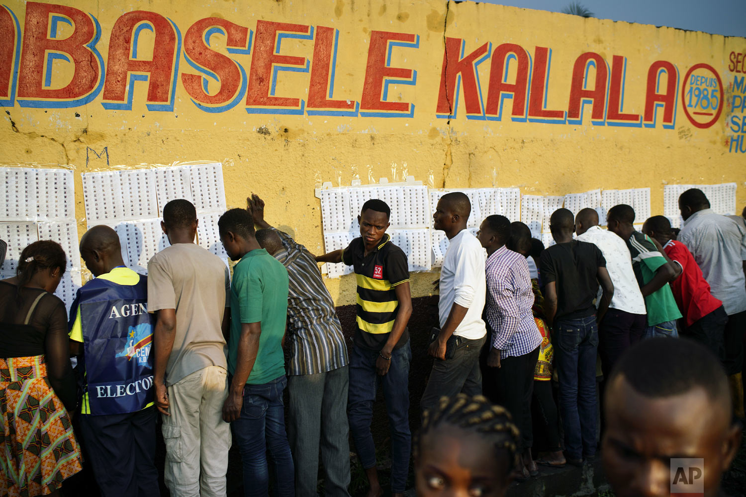  Election officials tape voter registration lists to a wall of the Les Anges primary school in Kinshasa, Congo, as voters start to check their names, Sunday Dec. 30, 2018. The election process was delayed when voters burned six voting machines and ba