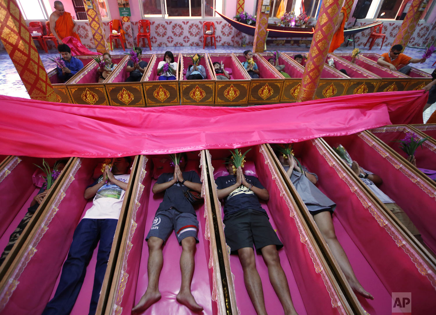  People pray as they take turns lying inside coffins at the Takien temple in suburban Bangkok, Thailand on Monday, Dec. 31, 2018. Worshippers believe that the ceremony – symbolizing death and rebirth – helps them rid themselves of bad luck and gives 