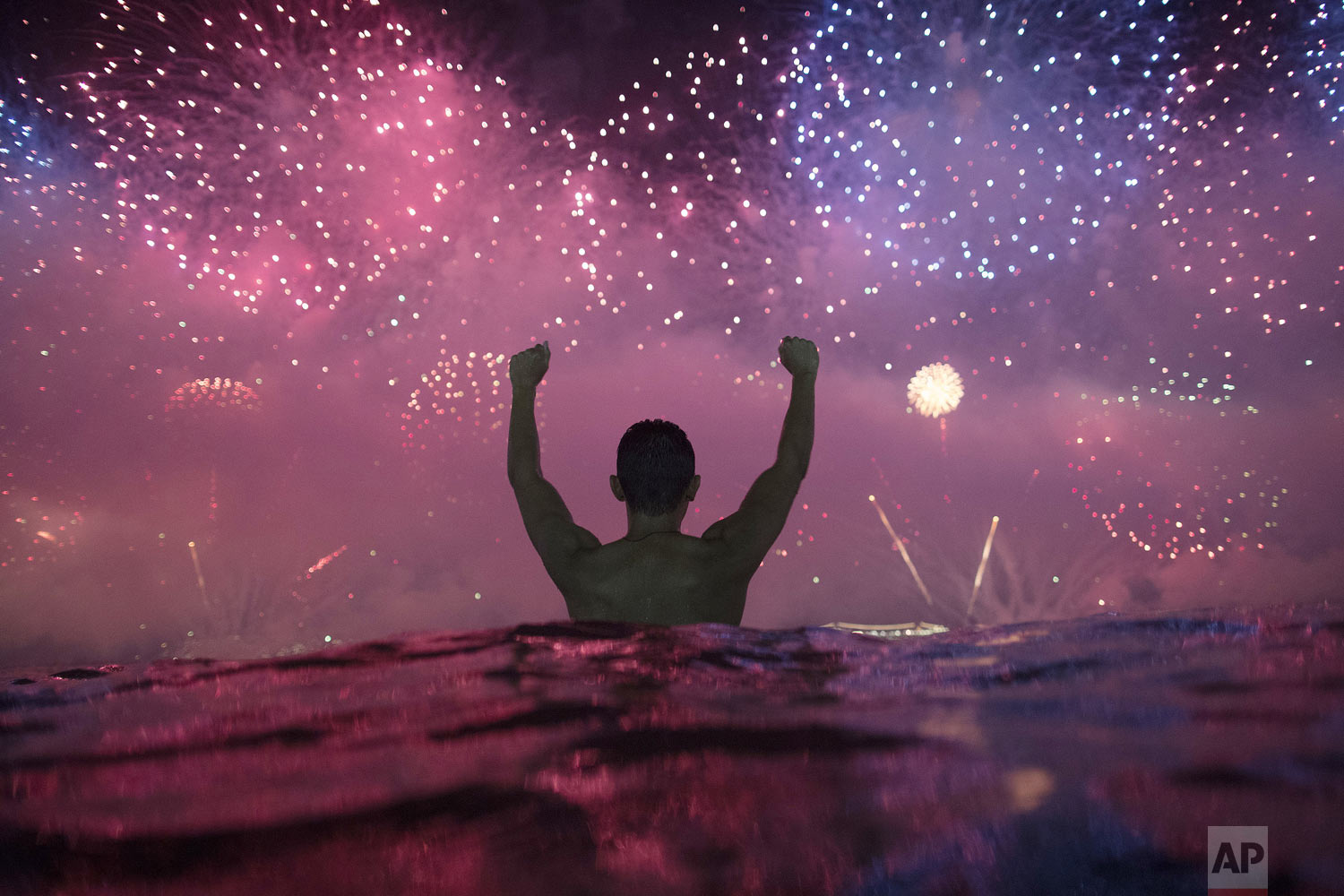  A man stands in the water as he watches fireworks over Copacabana Beach during New Year's celebrations in Rio de Janeiro, Brazil, Tuesday, Jan. 1, 2019. (AP Photo/Leo Correa) 