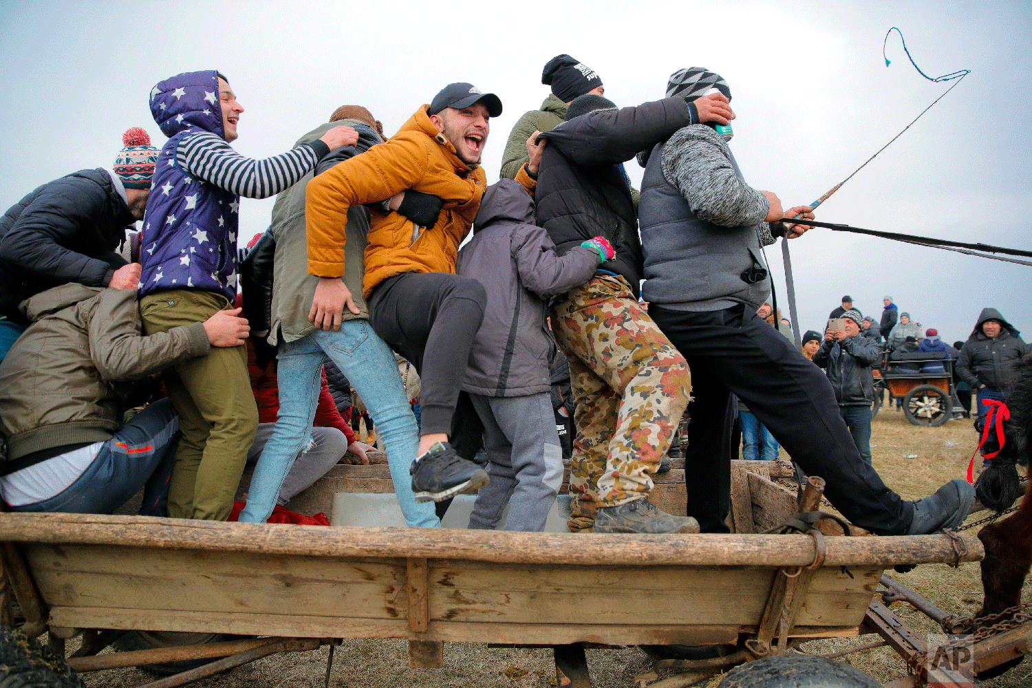 People cheer while riding in a horse down cart past an Orthodox priest sprinkling holy water on horses and people during Epiphany celebrations in Pietrosani, Romania, Sunday, Jan. 6, 2019. (AP Photo/Vadim Ghirda)