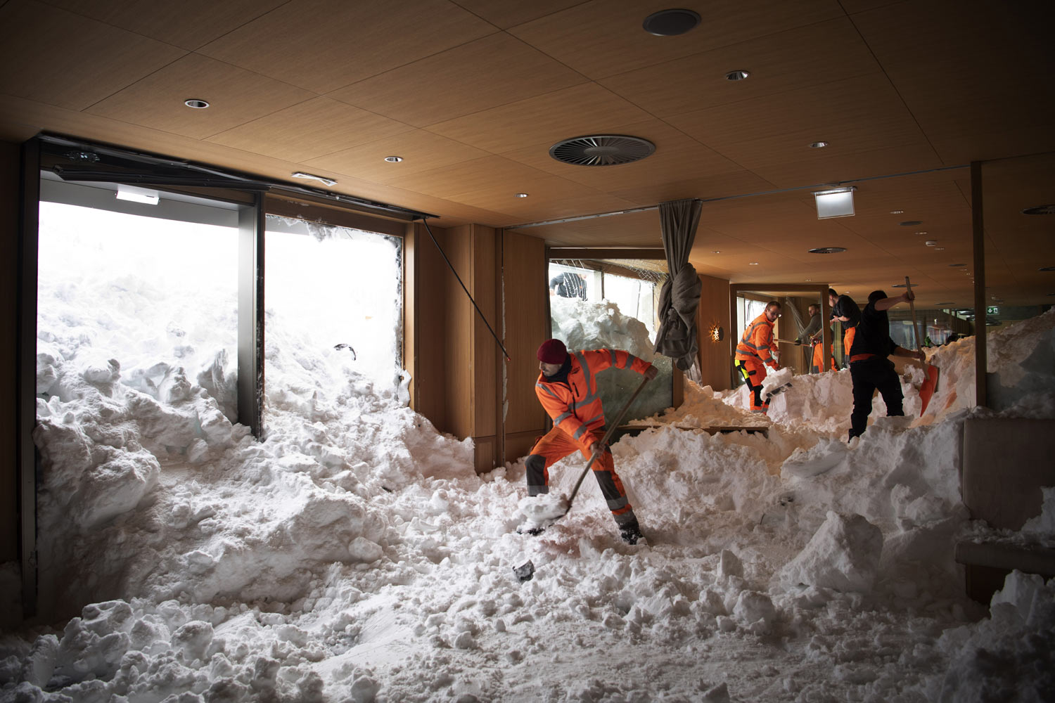 People clear snow from inside the Hotel Saentis in Schwaegalp, Switzerland, on Friday Jan. 11, 2019, after an avalanche. Police said three people were slightly hurt when the avalanche struck on Thursday afternoon. (Gian Ehrenzeller/Keystone via AP)