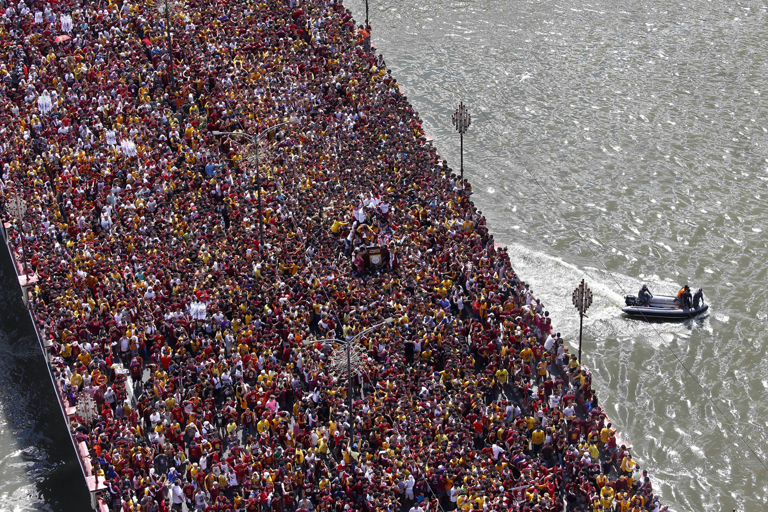 Philippine Coast Guard members keep watch as Roman Catholic devotees cross a bridge in a procession of the Black Nazarene to celebrate its feast day Wednesday, Jan. 9, 2019, in Manila, Philippines. Tens of thousands joined the annual procession of a centuries-old statue of Jesus Christ to celebrate the Feast of the Black Nazarene which usually ends before dawn the next day. (AP Photo/Bullit Marquez)