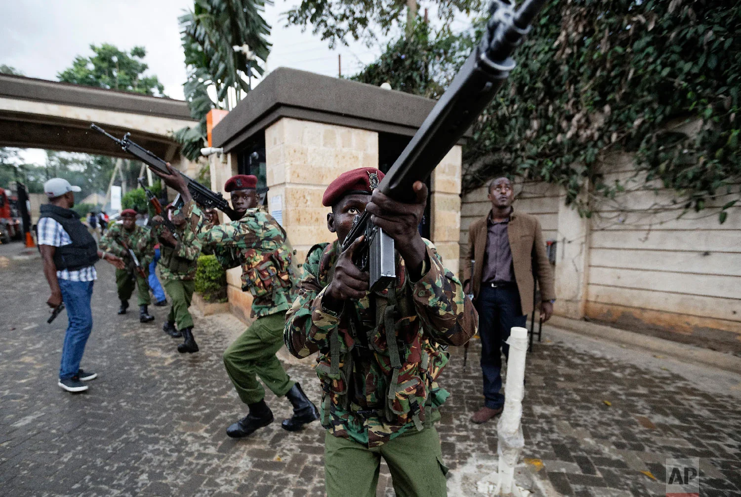 Kenyan security forces aim their weapons up at buildings as they run through a hotel complex in Nairobi, Kenya, Jan. 15, 2019. (AP Photo/Ben Curtis)