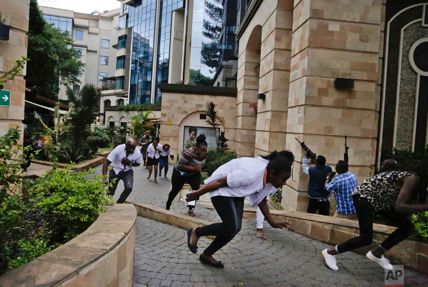 Civilians flee as security forces aim their weapons at the buildings of a hotel complex in Nairobi, Kenya, Jan. 15, 2019. (AP Photo/Khalil Senosi)