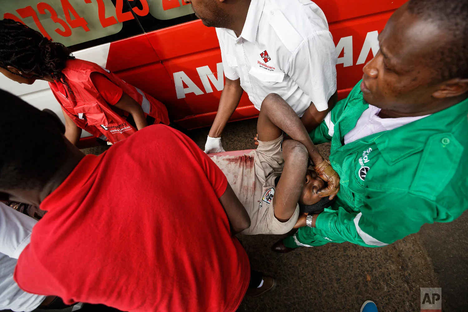 A wounded member of Kenyan special forces is carried from a US embassy diplomatic vehicle into an ambulance by paramedics at the scene Jan. 16, 2019 in Nairobi, Kenya. (AP Photo/Ben Curtis)