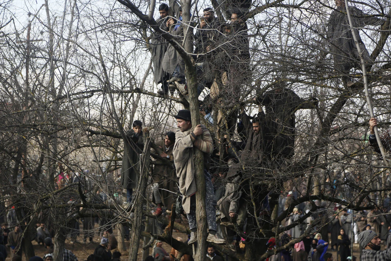 Kashmiri villagers watch the funeral of rebel commander Zeenatul Islam in Sugan village, 61 kilometers (38 miles) south of Srinagar, Indian controlled Kashmir, on Sunday, Jan. 13, 2019. Massive anti-India protests and clashes erupted in disputed Kashmir on Sunday, leading to injuries to at least 16 people after a gunbattle between militants and government forces overnight killed two rebels, police and residents said. (AP Photo/Mukhtar Khan)