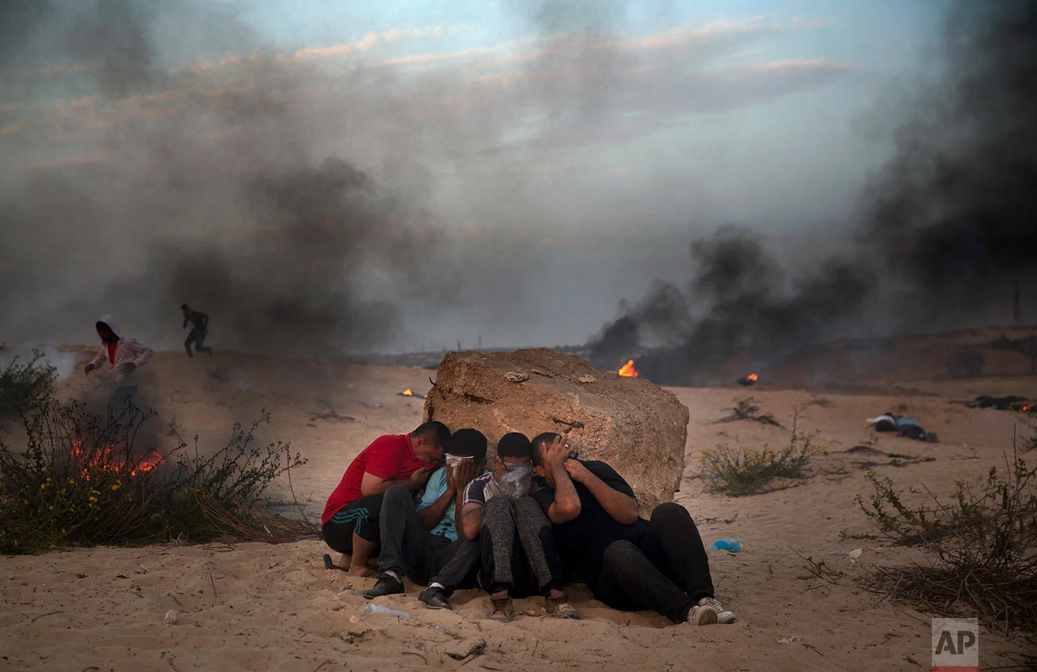 Palestinian protesters cover their faces from teargas fires by Israeli troops during a protest on the beach at the border with Israel near Beit Lahiya, northern Gaza Strip, Oct. 22, 2018. (AP Photo/Khalil Hamra)
