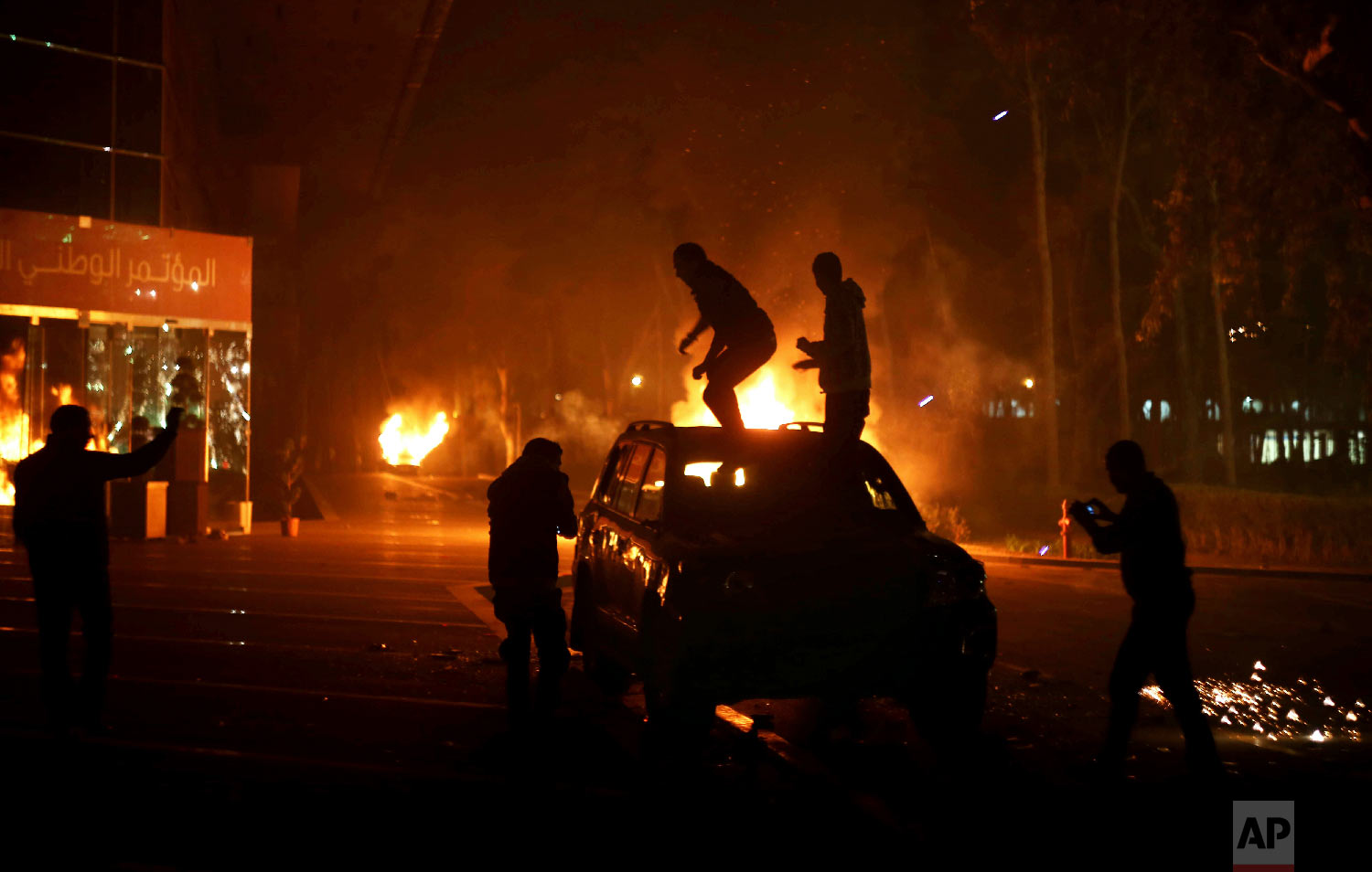  Protesters stand atop a vehicle as others burn in front of the National Conference Hall, in Tripoli, Libya, March 2, 2014.  (AP Photo/Mohamed Ben Khalifa) 
