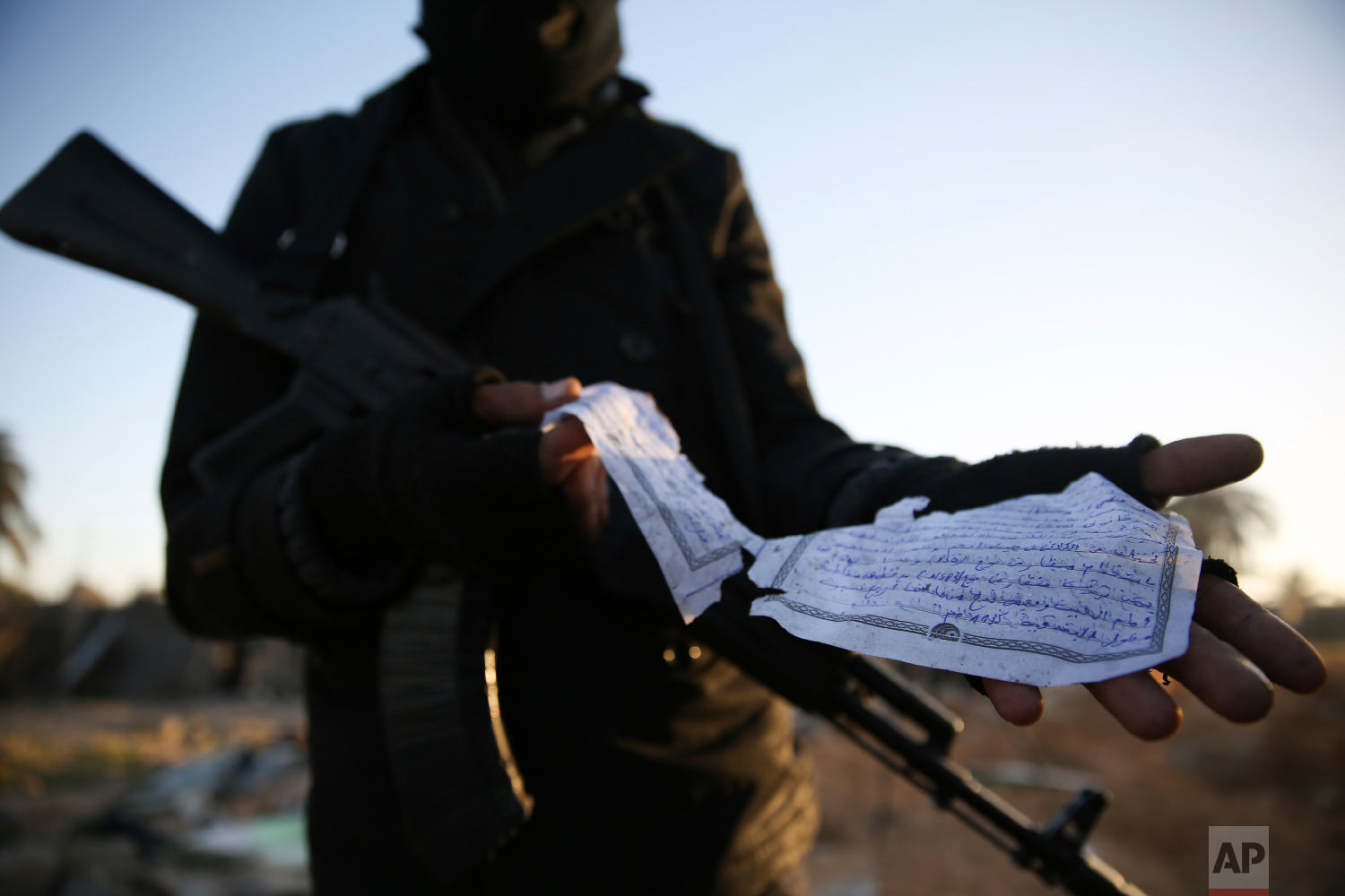  A member of the Libyan security forces displays part of a document in Arabic describing weaponry, that was found at the site of U.S. airstrikes on an Islamic State camp that killed dozens, near the western city of Sabratha, Libya, Feb. 20, 2016. (AP
