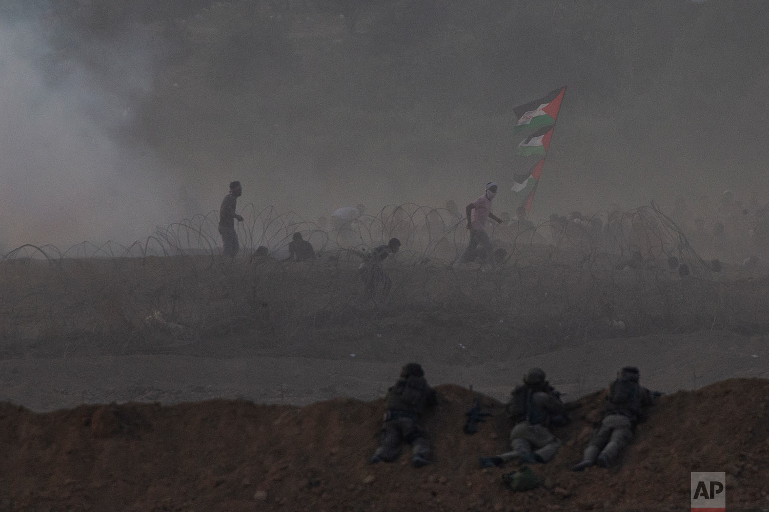  Israeli soldiers are positioned on a sand berm as Palestinian protesters run during a protest along the Israel Gaza border in Israel, Friday, Oct. 19, 2018. (AP Photo/Ariel Schalit) 