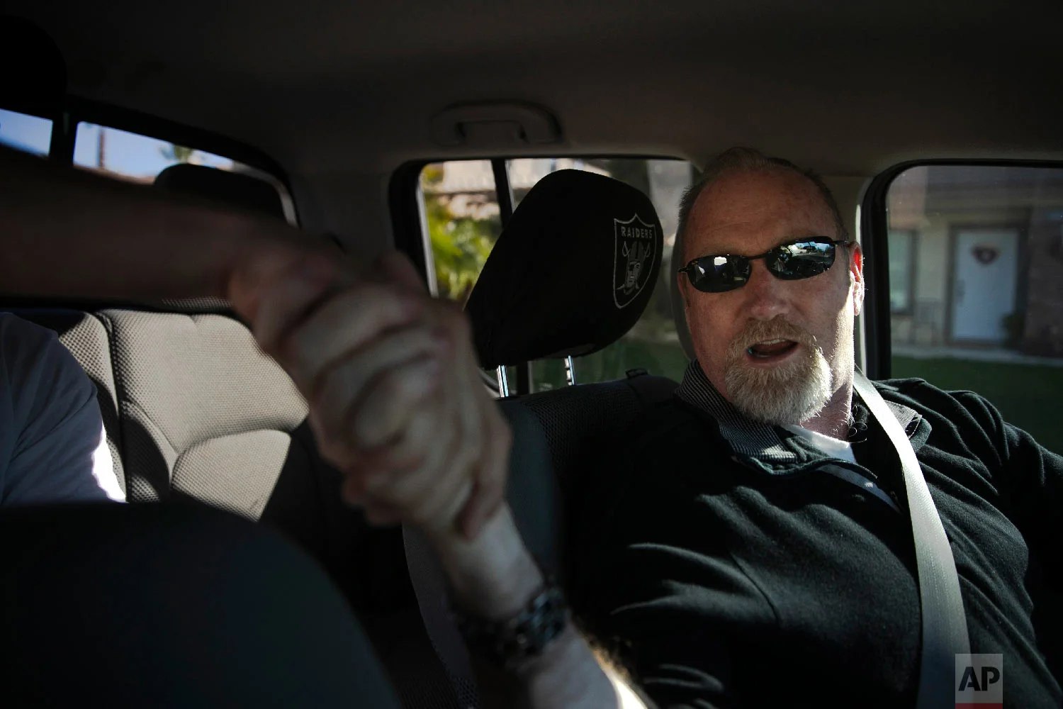 Chris George, a federal employee furloughed from his job as a forestry technician supervisor for the U.S. Department of Agriculture Forest Service, shakes hands with a passenger in his pickup truck while driving for Lyft to make ends meet Monday, Jan. 21, 2019, in Redlands, Calif. (AP Photo/Jae C. Hong)