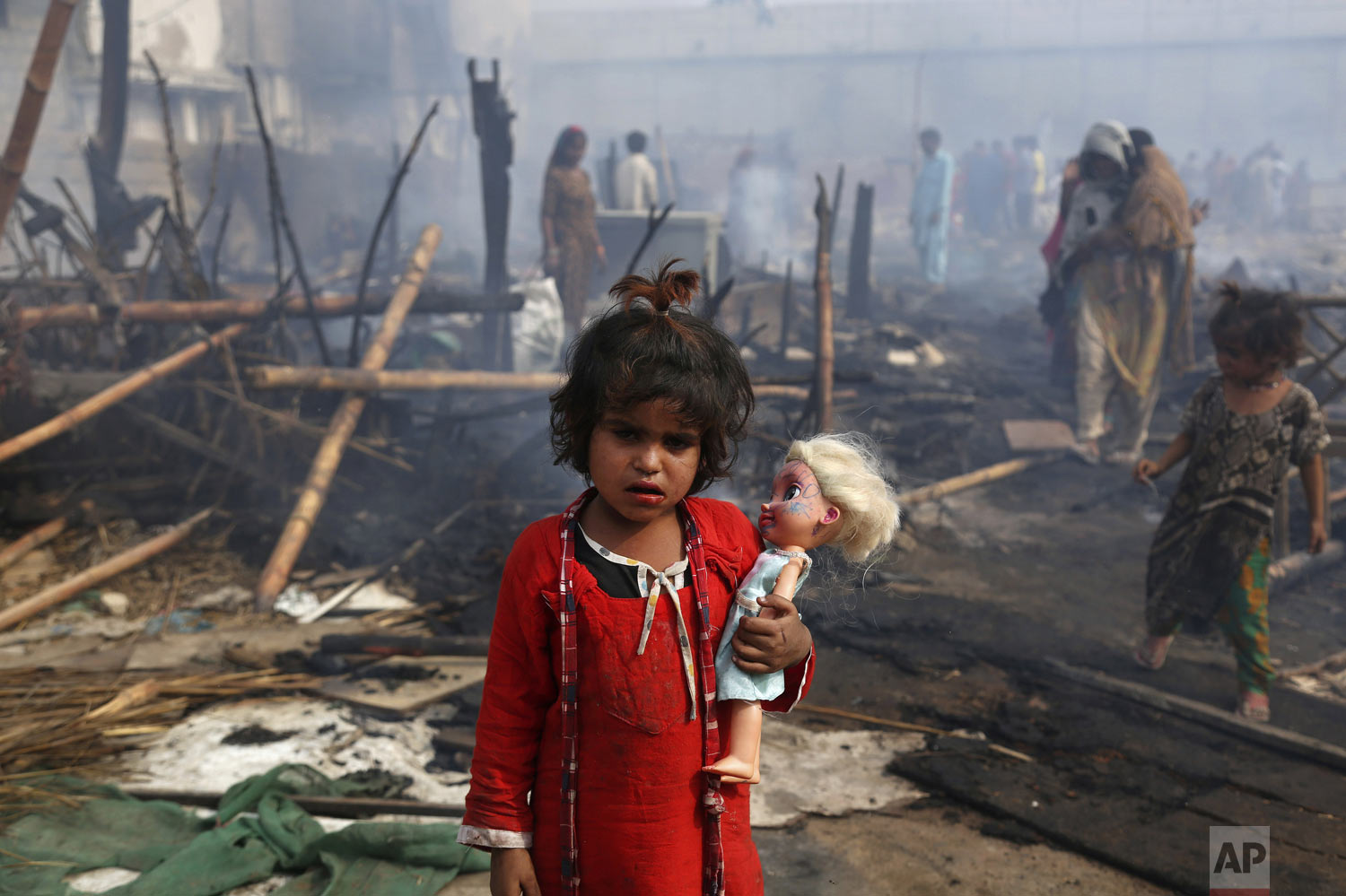  A young girl holds her doll while standing amid the ruins of her burnt home after a fire gutted the area, in Karachi, Pakistan, Sunday, Jan. 20, 2019. About 40 huts were burned to ashes as fire erupted early Sunday morning, making dozens of families