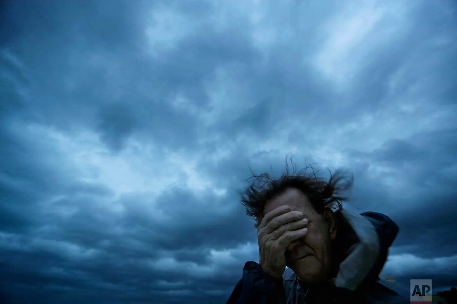 Russ Lewis covers his eyes from a gust of wind and a blast of sand as Hurricane Florence approaches Myrtle Beach, S.C., Friday, Sept. 14, 2018. (AP Photo/David Goldman)