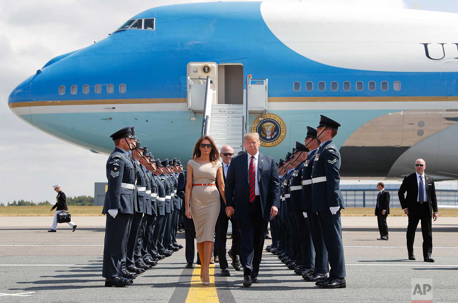 U.S. President Donald Trump and first lady Melania Trump walk across the tarmac after stepping off Air Force One as they arrive at London's Stansted Airport, Thursday, July 12, 2018. Walking directly behind them is Woody Johnson, center, United States Ambassador to the United Kingdom. (AP Photo/Pablo Martinez Monsivais)