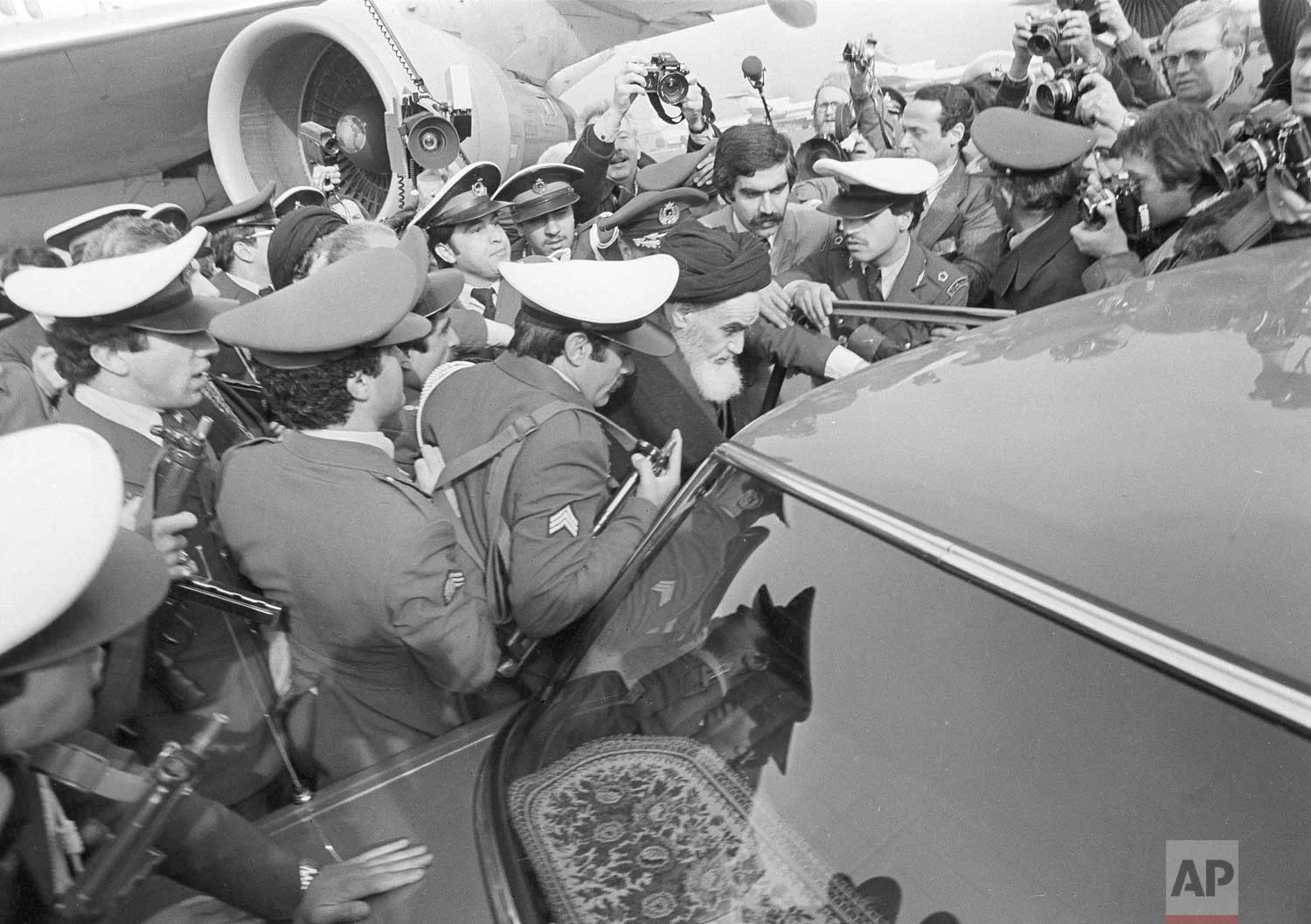 In this Feb. 1, 1979 photo, exiled Ayatollah Ruhollah Khomeini has a heavy escort as he enters car to leave the airport in Tehran, Iran. (AP Photo)