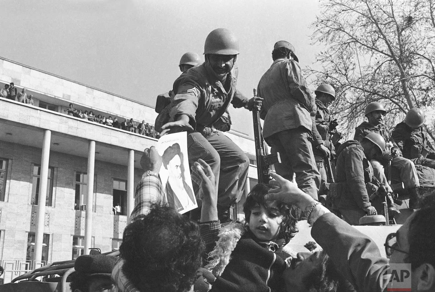  In this Jan. 15, 1979 photo, a smiling Iranian soldier is hailed by demonstrators who decorated them with flowers and pictures of Ayatollah Ruhollah Khomeini, in Tehran, Iran.  (AP Photo) 