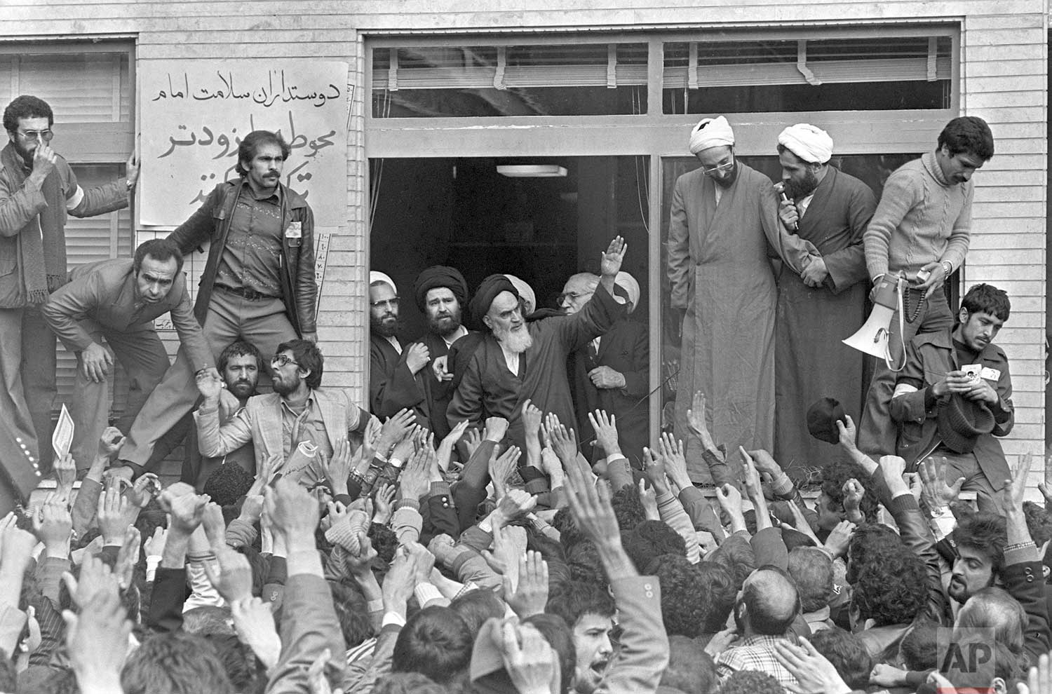  In this Feb. 1, 1979 photo, Ayatollah Ruhollah Khomeini, center, waves to followers as he appears on the balcony of his headquarters in Tehran, Iran. (AP Photo/Campion) 