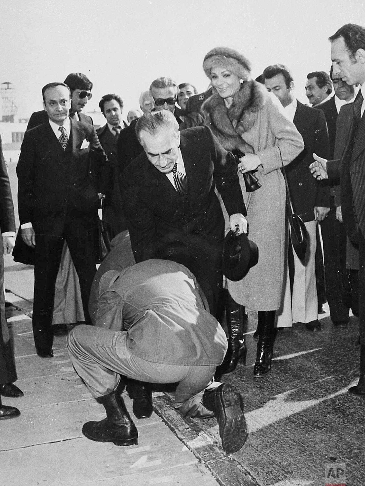  In this Jan. 16, 1979 photo, a soldier bends to kiss the feet of Iran's Shah Mohammad Reza Pahlavi on the tarmac of Mehrabad Airport in Tehran, Iran. Behind the shah is his wife, Empress Farah. (AP Photo) 