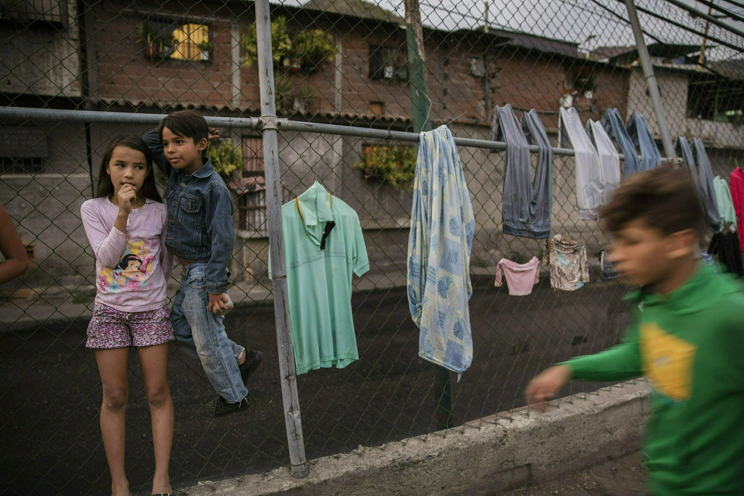 Valentina Gonzalez, 10, left, and her friend Engleston Gonzalez, 8, stand next to clothes drying on a fence in Caracas, Venezuela, Tuesday, Jan. 29, 2019. Venezuela's President Nicolas Maduro went on state television Tuesday to announce that he was beefing up the nation's defense by expanding Venezuela's civilian armed militia to 2 million members. The reserve force was created by the late Hugo Chavez to train civilians to assist the armed forces and defend the socialist revolution from attacks. (AP Photo/Rodrigo Abd)