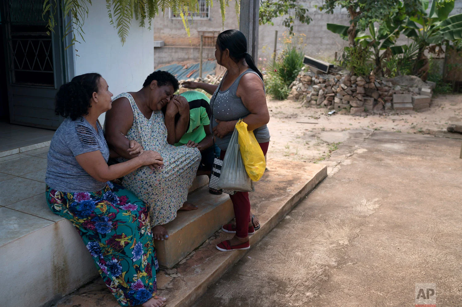 Malvina Firmina Nunes and her son Fernando are comforted by friends at their home as they grieve for their missing 35-year-old son and brother, Peterson, after a deadly Vale dam collapse in Brumadinho, Brazil, Jan. 30, 2019. (AP Photo/Leo Correa)