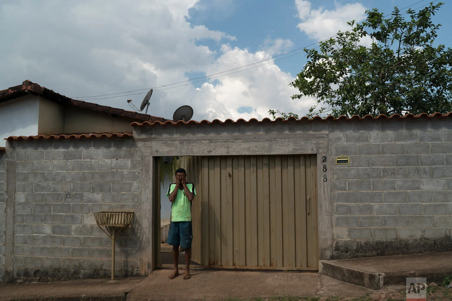 Fernando Nunes wipes tears from his face at the doorway of his home, where the wall carries the Portuguese message: "Vale assassin" in Brumadinho, Brazil, Jan. 30, 2019. (AP Photo/Leo Correa)
