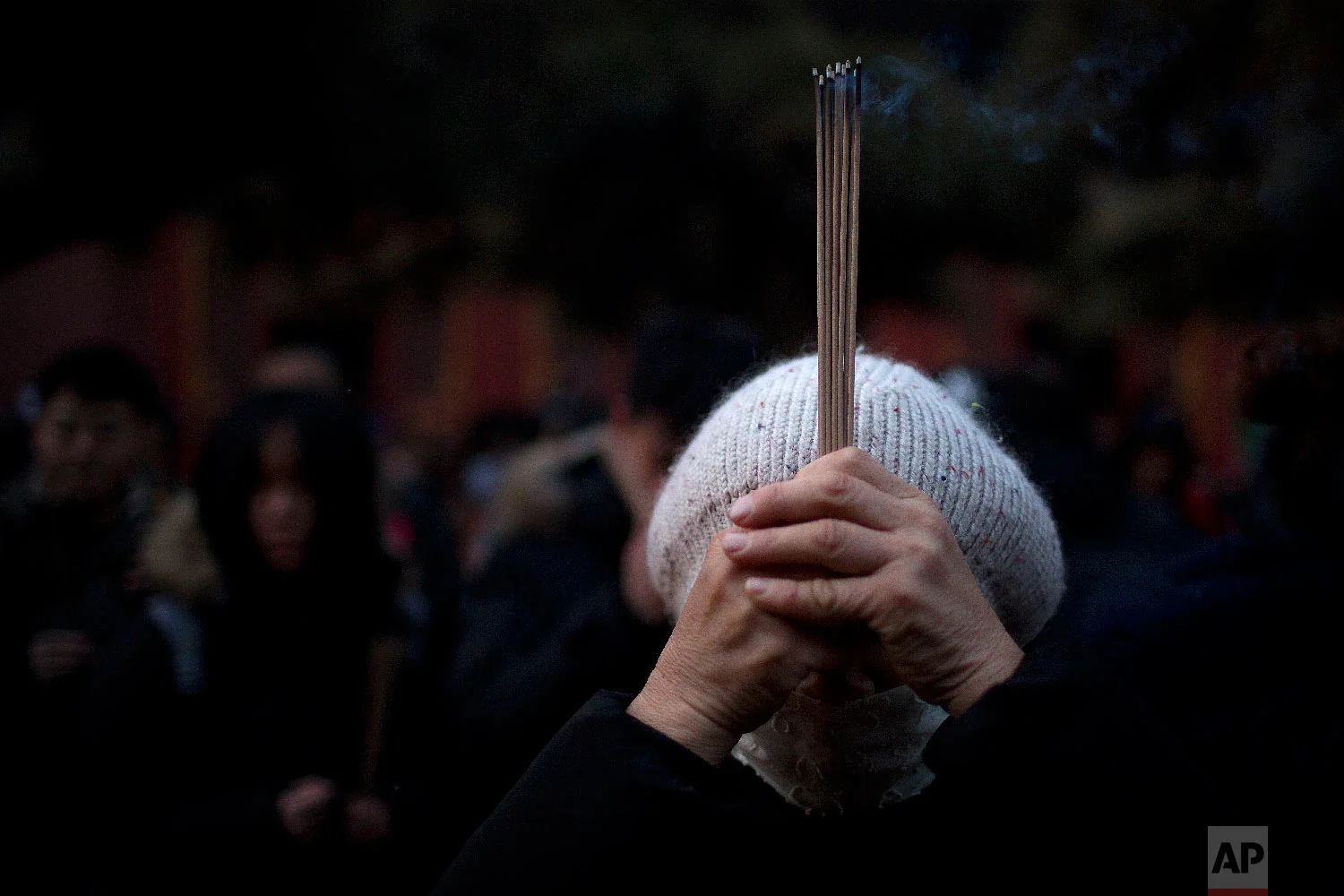 A woman holds sticks of incense as she prays at the Lama Temple in Beijing, Tuesday, Feb. 5, 2019. (AP Photo/Mark Schiefelbein)