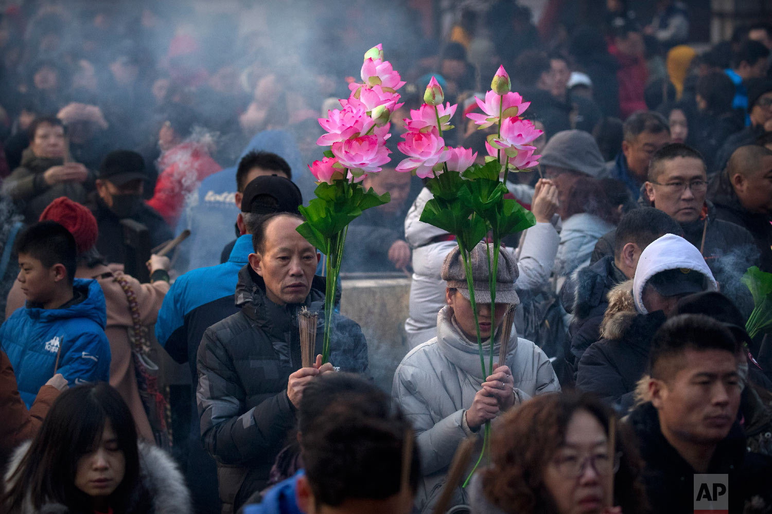  People hold floral bouquets and sticks of incense as they pray at the Lama Temple in Beijing, Tuesday, Feb. 5, 2019. (AP Photo/Mark Schiefelbein) 