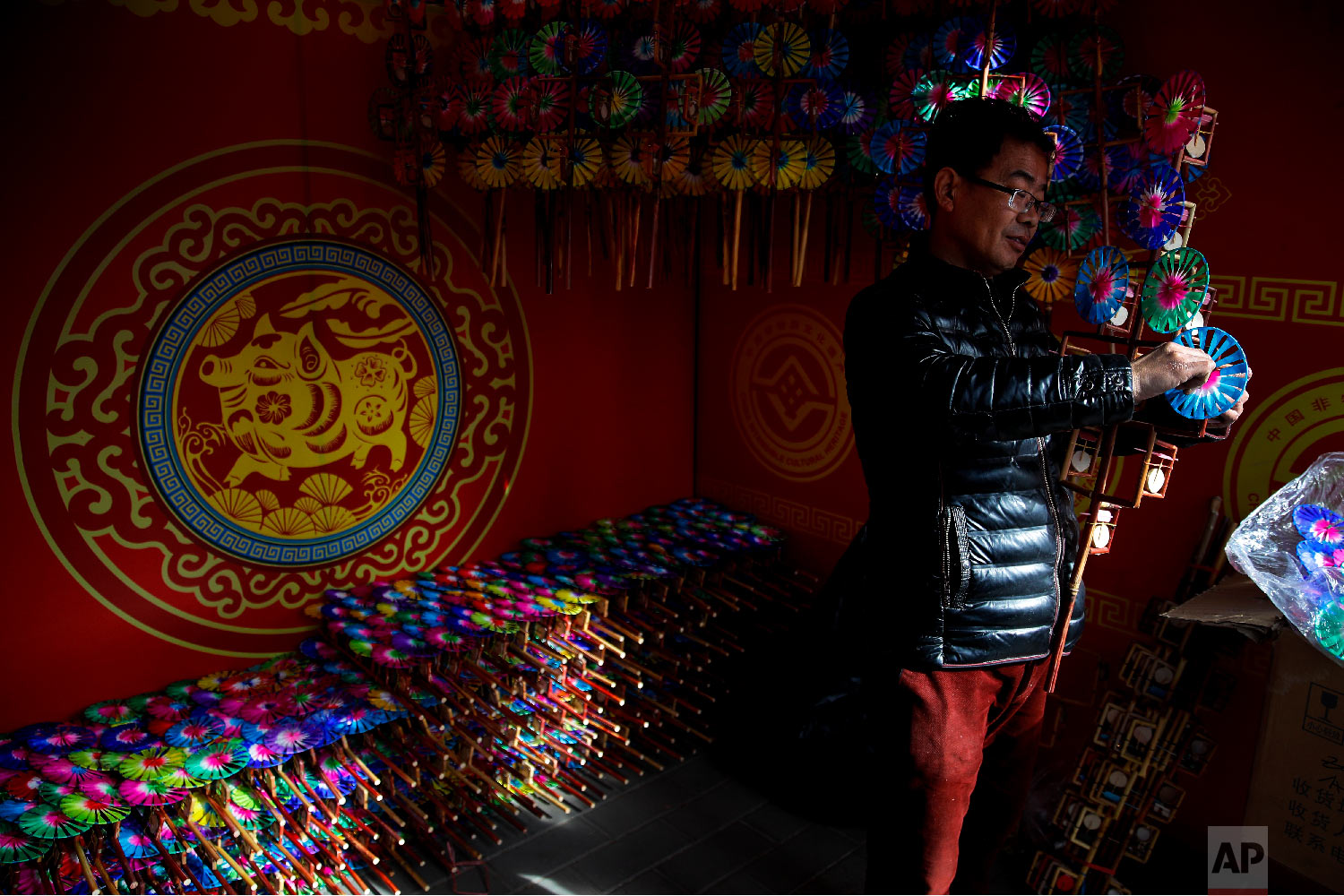  A vendor adds a wooden windmill toy to his store at the Longtan Park for a temple fair ahead of Chinese Lunar New Year in Beijing, Sunday, Feb. 3, 2019. (AP Photo/Andy Wong) 