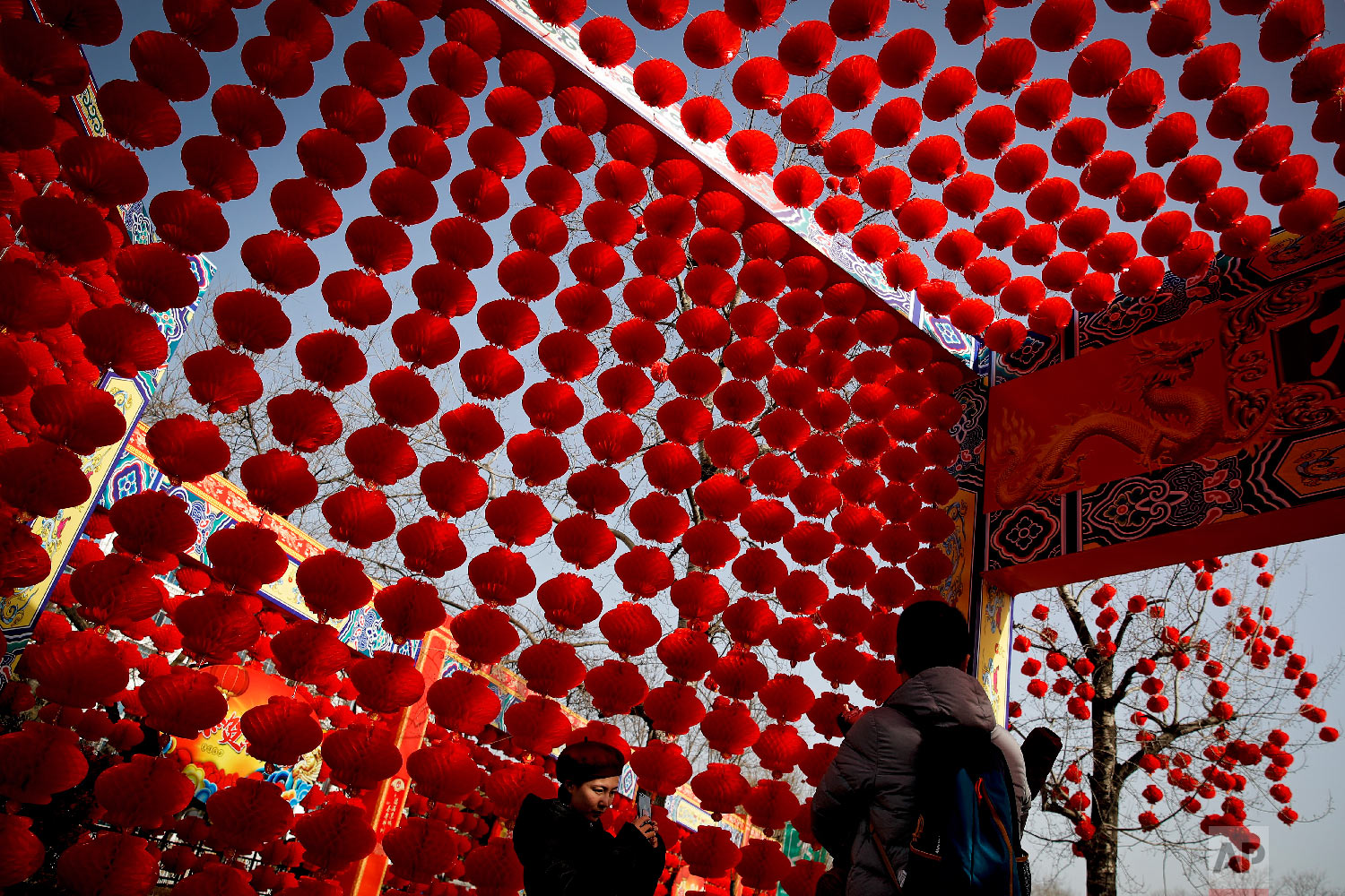  A woman takes a souvenir photo of her family posing in front of red lanterns on display at the Longtan Park for a temple fair ahead of Chinese Lunar New Year in Beijing, Sunday, Feb. 3, 2019. (AP Photo/Andy Wong) 