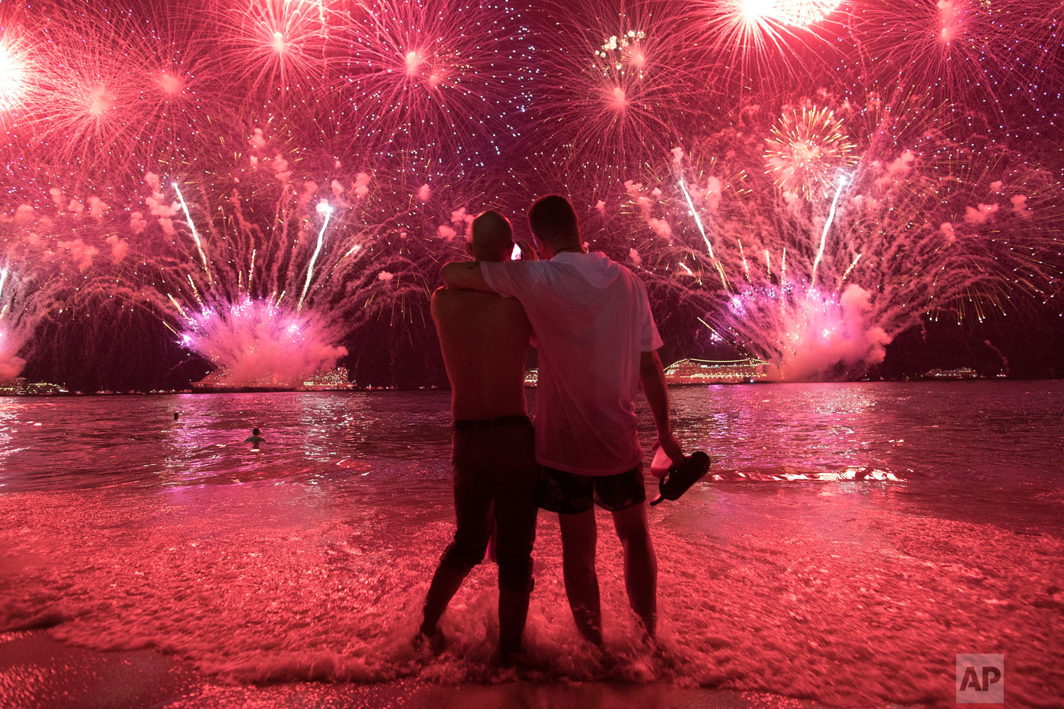  Men watch fireworks exploding over Copacabana beach for the New Year's celebrations in Rio de Janeiro, Brazil, Jan. 1, 2019. (AP Photo/Leo Correa) 