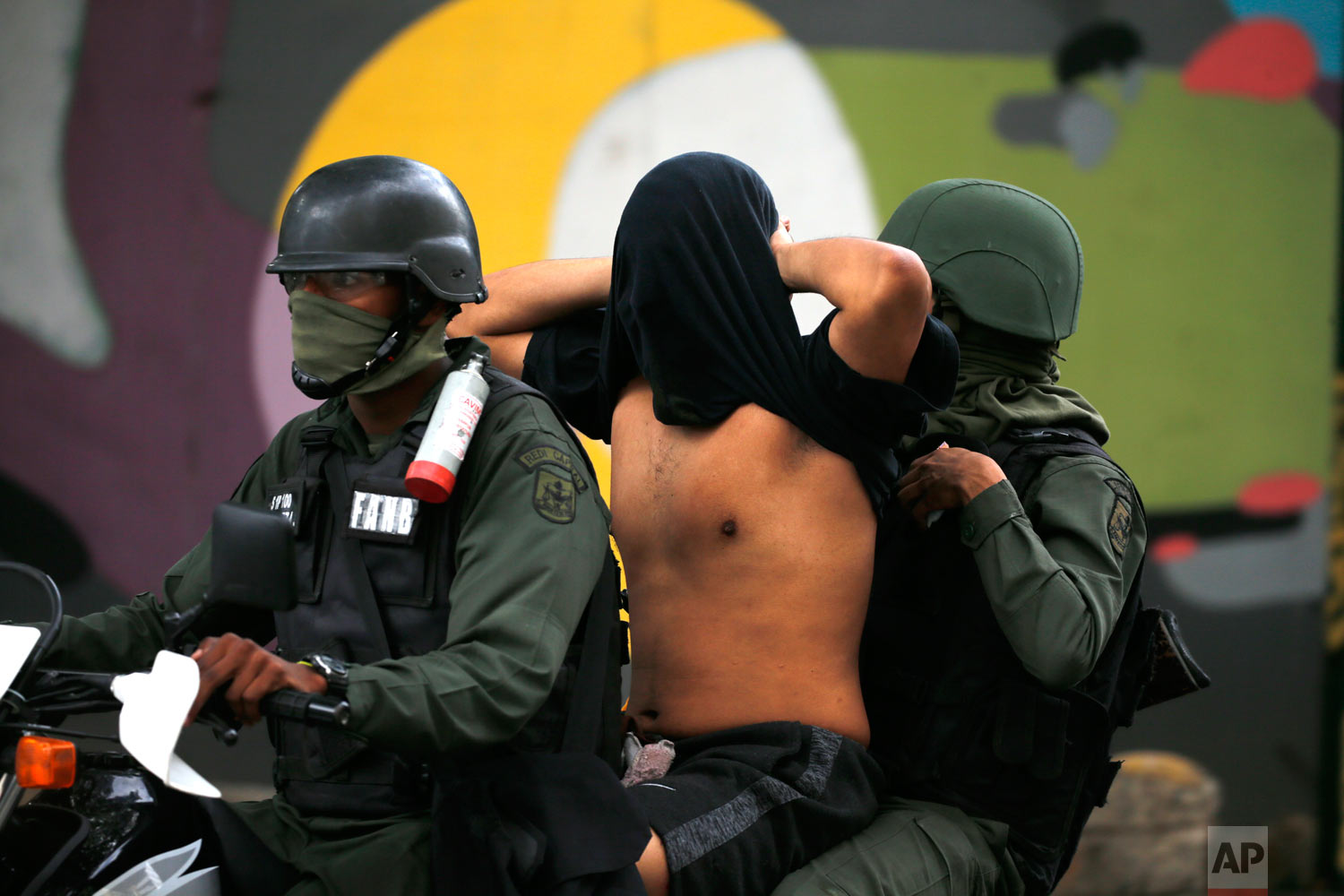  National Guard soldiers detain an anti-government protester, whose face they covered, after a rally demanding the resignation of President Nicolas Maduro in Caracas, Venezuela, Jan. 23, 2019. (AP Photo/Fernando Llano) 