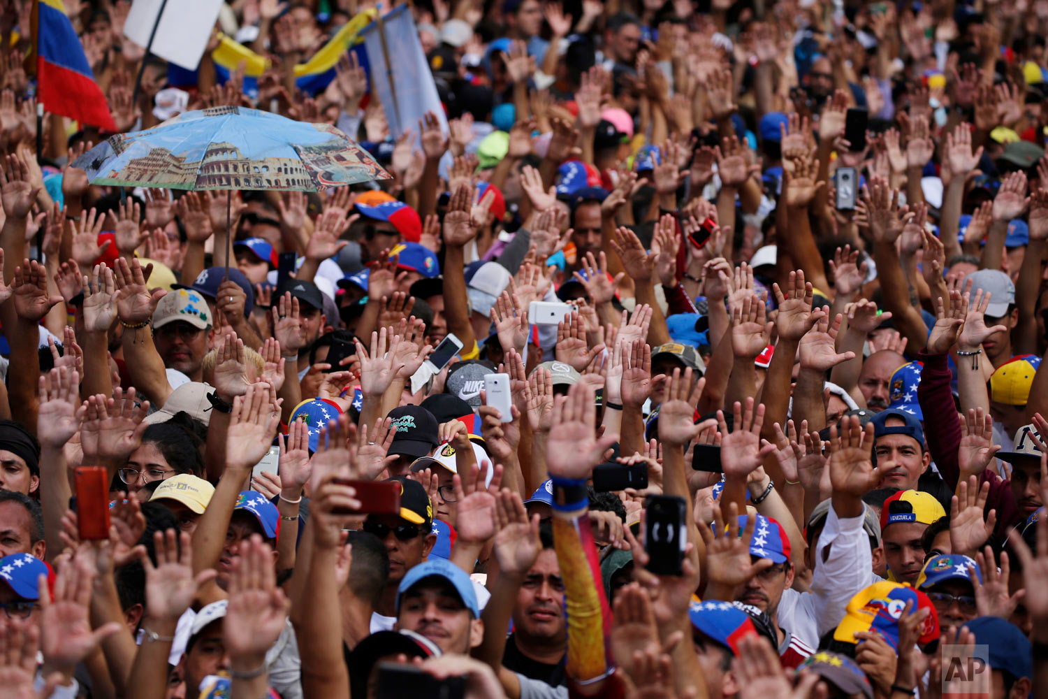  Anti-government protesters hold their hands up during the symbolic swearing-in of Juan Guaido, head of the opposition-run congress, who declared himself interim president of Venezuela, during a rally demanding President Nicolas Maduro's resignation 