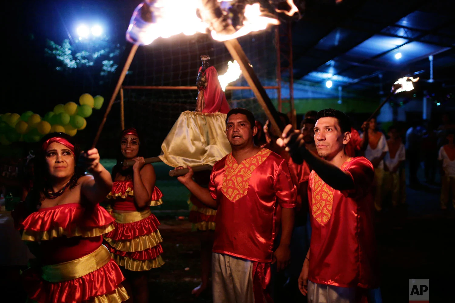 Adolfo Bogarin, president of the Afro-Paraguayan cultural group Kamba Cua, center, helps carry a statue of Saint Balthazar, one of the Three Kings, as they hold a torch-lit procession to mark Epiphany in Fernando de la Mora, Paraguay, Jan. 5, 2019. (AP Photo/Jorge Saenz)