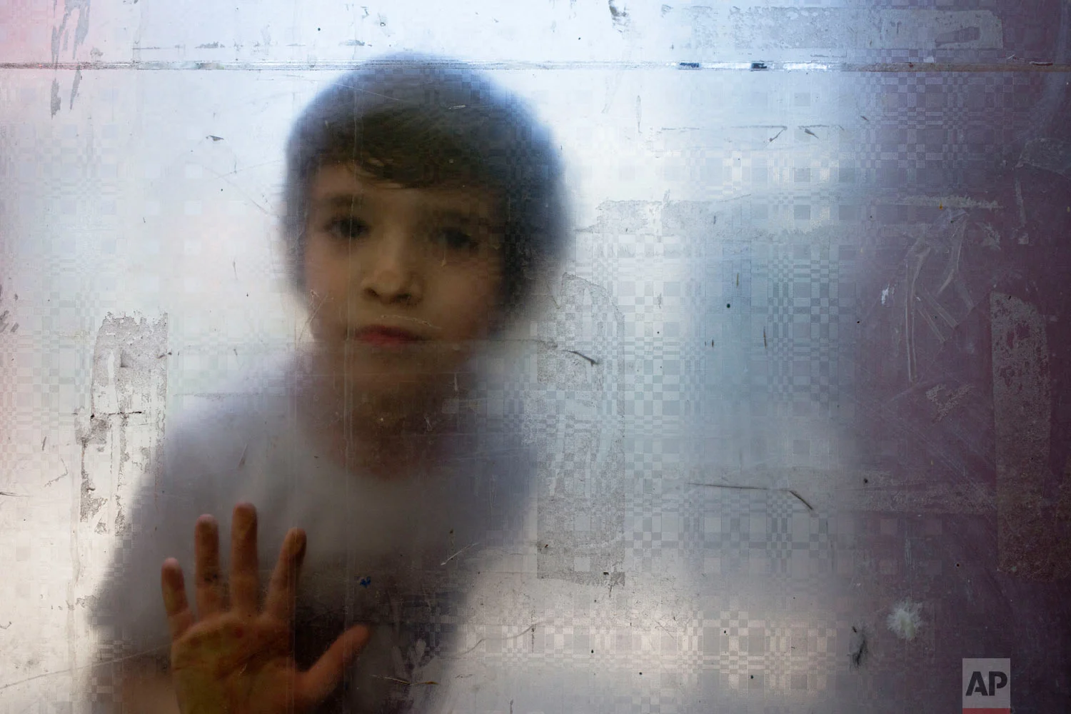 In this Dec.13, 2018 photo published in Jan. 2019, Laura, a transgender girl, looks through a glass door during recess at the Amaranta Gomez school for transgender children in Santiago, Chile. (AP Photo/Esteban Felix)