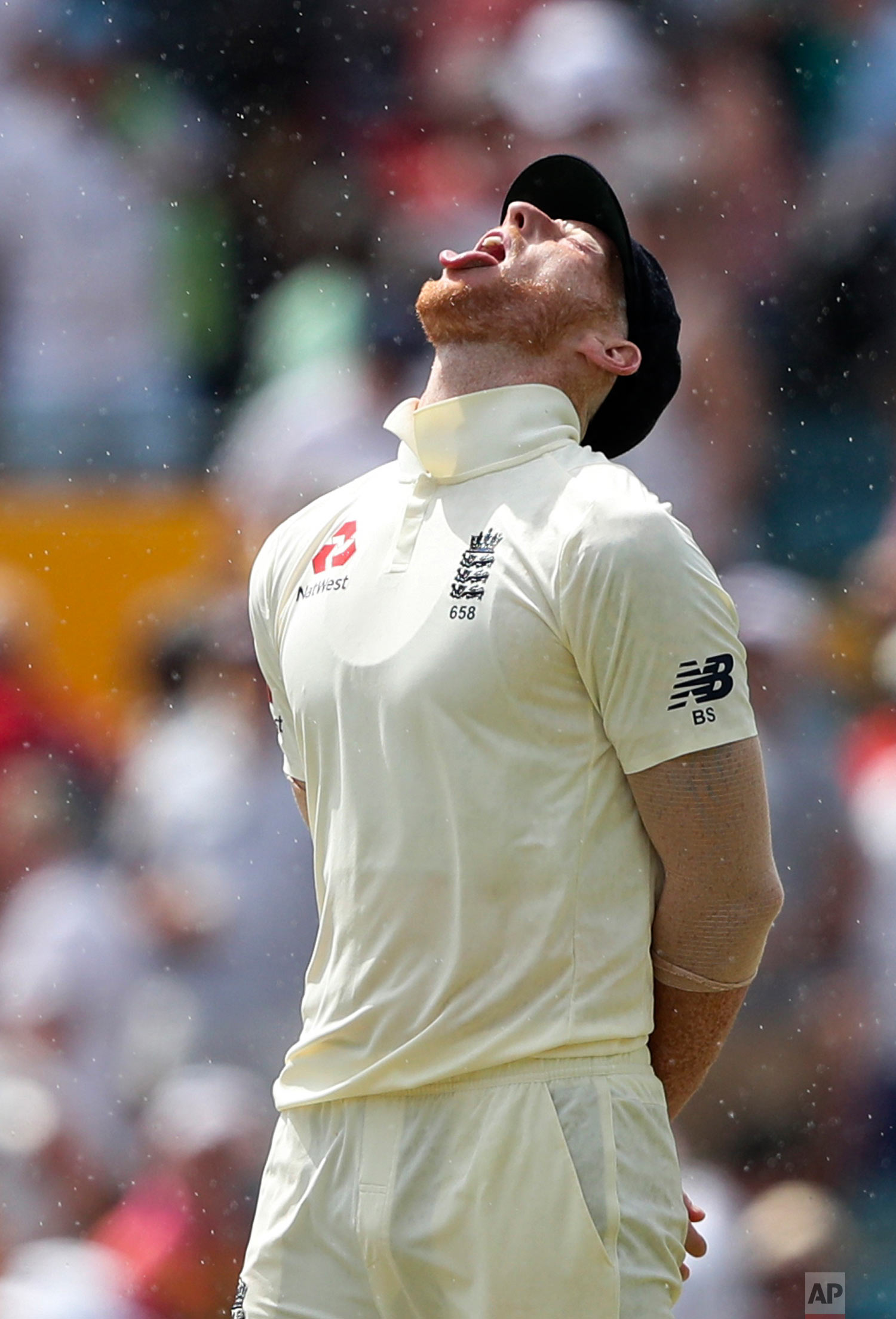  England's Ben Stokes opens his mouth to catch raindrops on the third day of the first cricket Test match against West Indies in Bridgetown, Barbados, Jan. 25, 2019. (AP Photo/Ricardo Mazalan) 