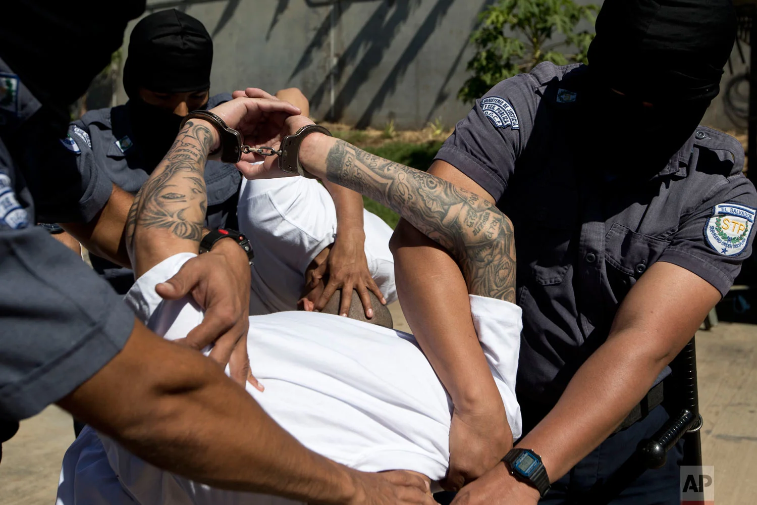 Jailed men identified by authorities as members of the Mara Salvatrucha gang are escorted in handcuffs by masked prison guards to the Zacatras high security prison where they will await trials for murder in Zacatecoluca, El Salvador, Jan. 31, 2019. (AP Photo/Moises Castillo)