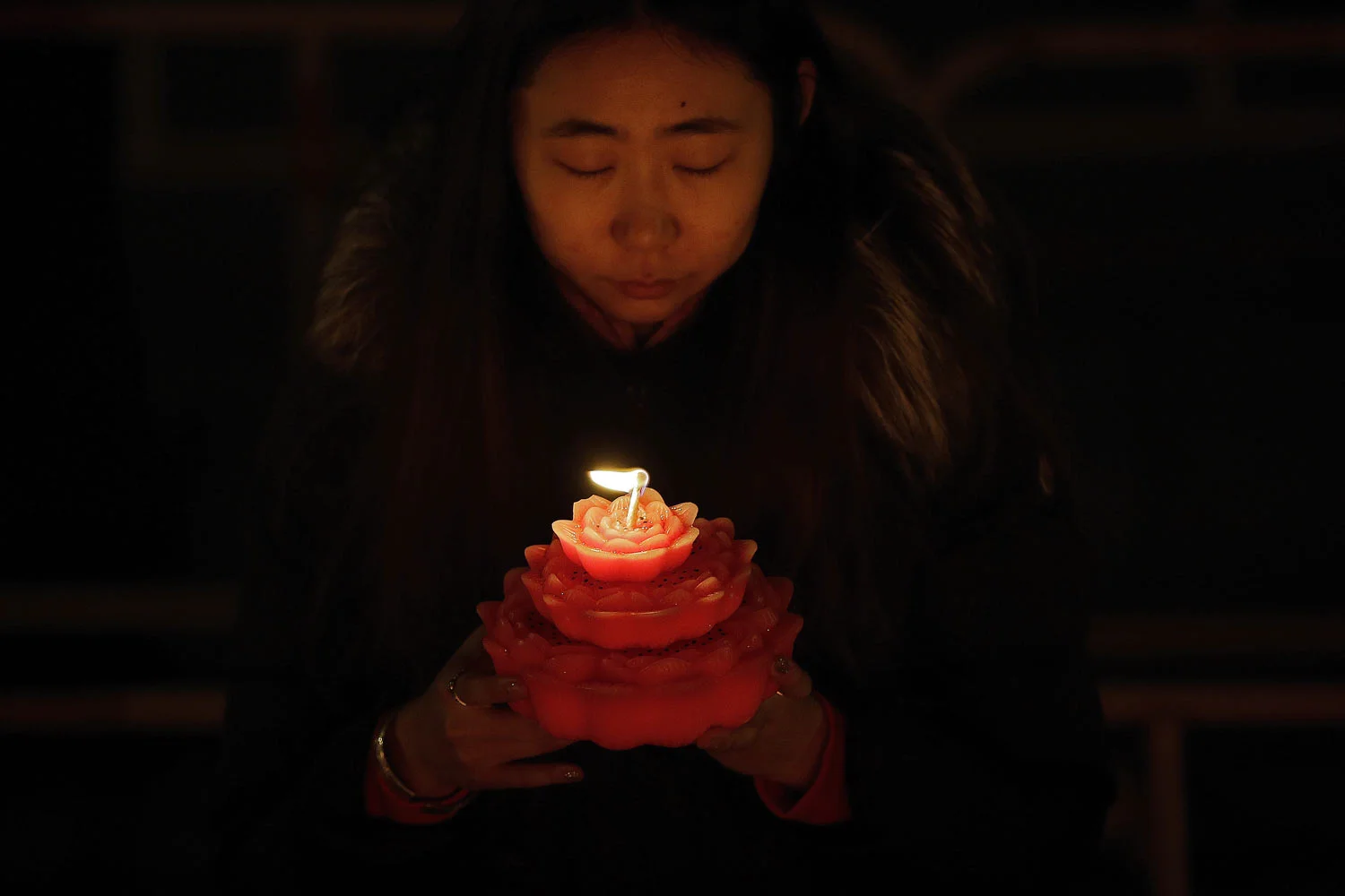 A woman holds a flower-shaped candle as she offers prayers on the first day of the Chinese Lunar New Year at the Tanzhe temple in the Mentougou District of Beijing, Tuesday, Feb. 5, 2019. The day ushers in the Year of the Pig on the Chinese zodiac. (AP Photo/Andy Wong)